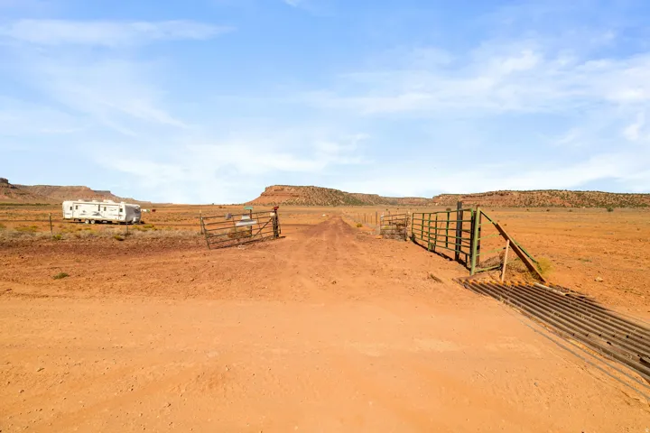 Expansive desert landscape featuring a dirt road and a cattle guard entry