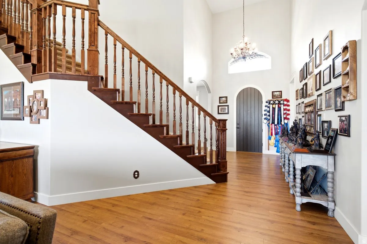 Grand foyer featuring a dramatic two-story ceiling, wood-finish flooring, and a substantial wooden staircase with turned balusters