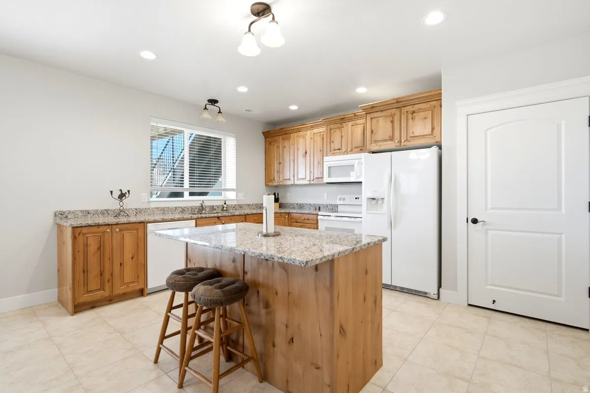 Kitchen featuring a central island with a granite countertop, wood cabinetry, and recessed lighting