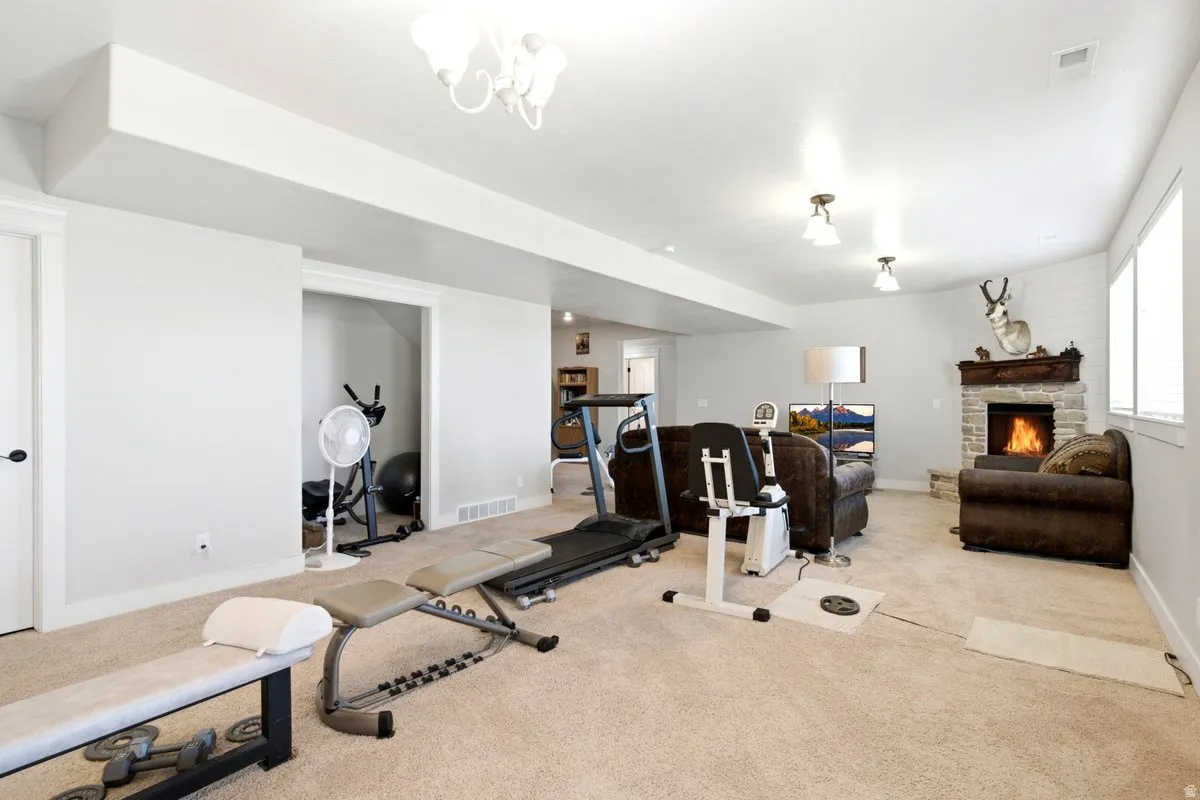 Spacious recreational room featuring a stone-clad fireplace with a decorative mantel, multiple windows for natural light, recessed lighting, and a white ceiling fan light fixture
