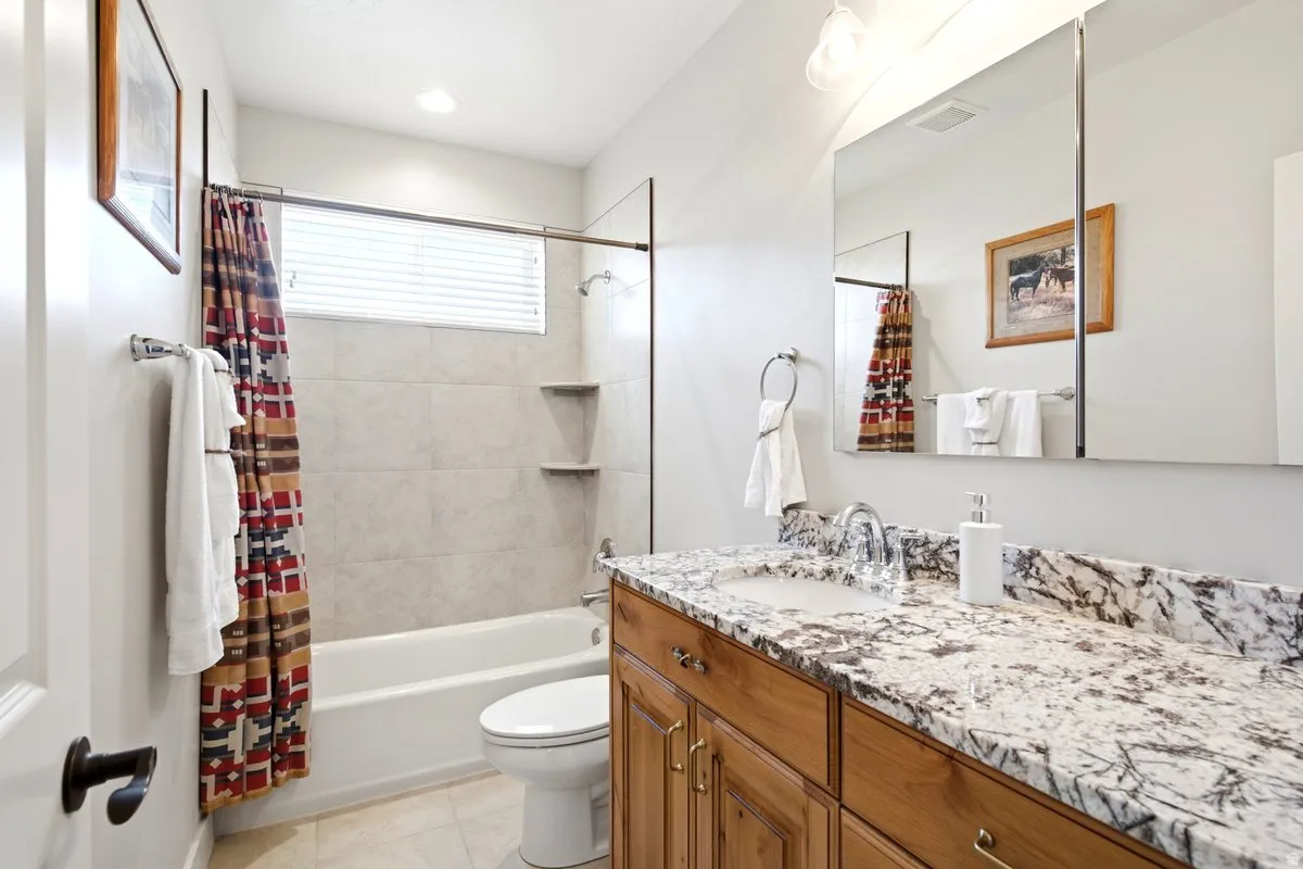 Bathroom featuring a vanity with a light-toned stone countertop, integrated sink, and wood cabinetry