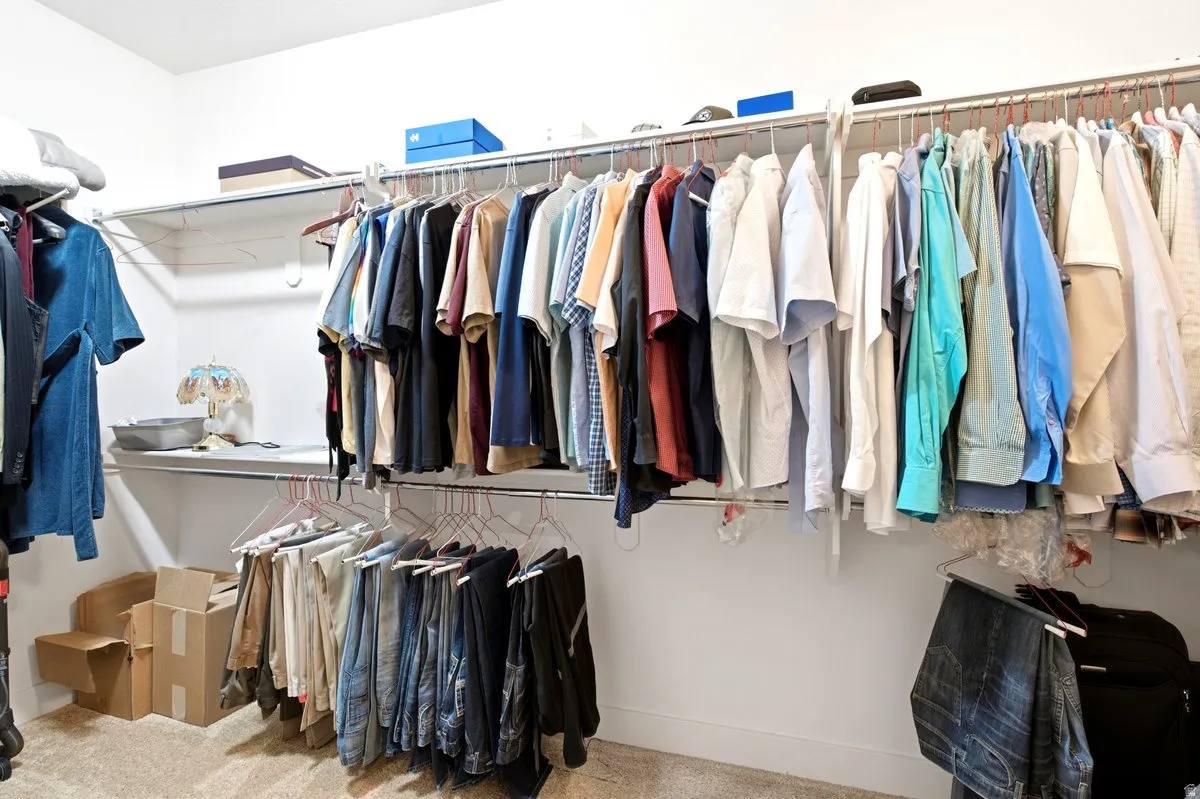 Walk-in closet featuring built-in shelving, multiple hanging rods, and carpet flooring