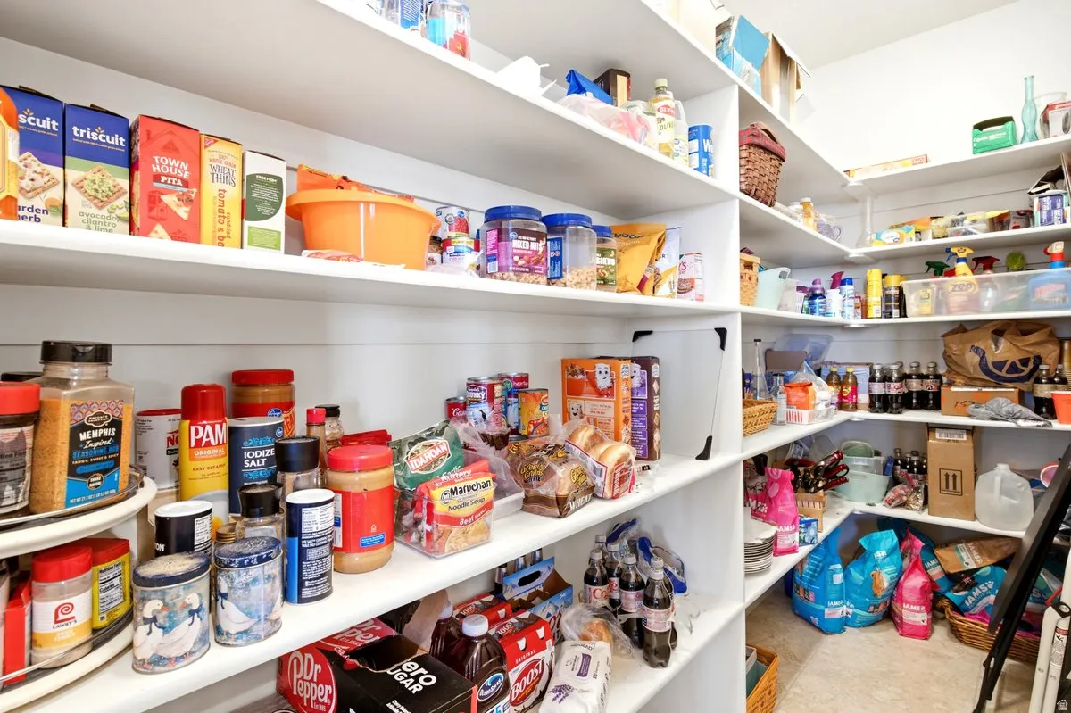 Corner pantry featuring extensive white shelving and light-colored flooring
