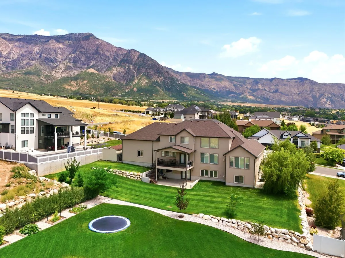 Expansive backyard featuring a manicured lawn, tiered landscaping with rock retaining walls, and mature trees
