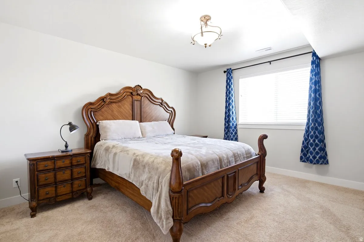Carpeted room featuring a ceiling-mounted light fixture, white walls, and a window with blinds