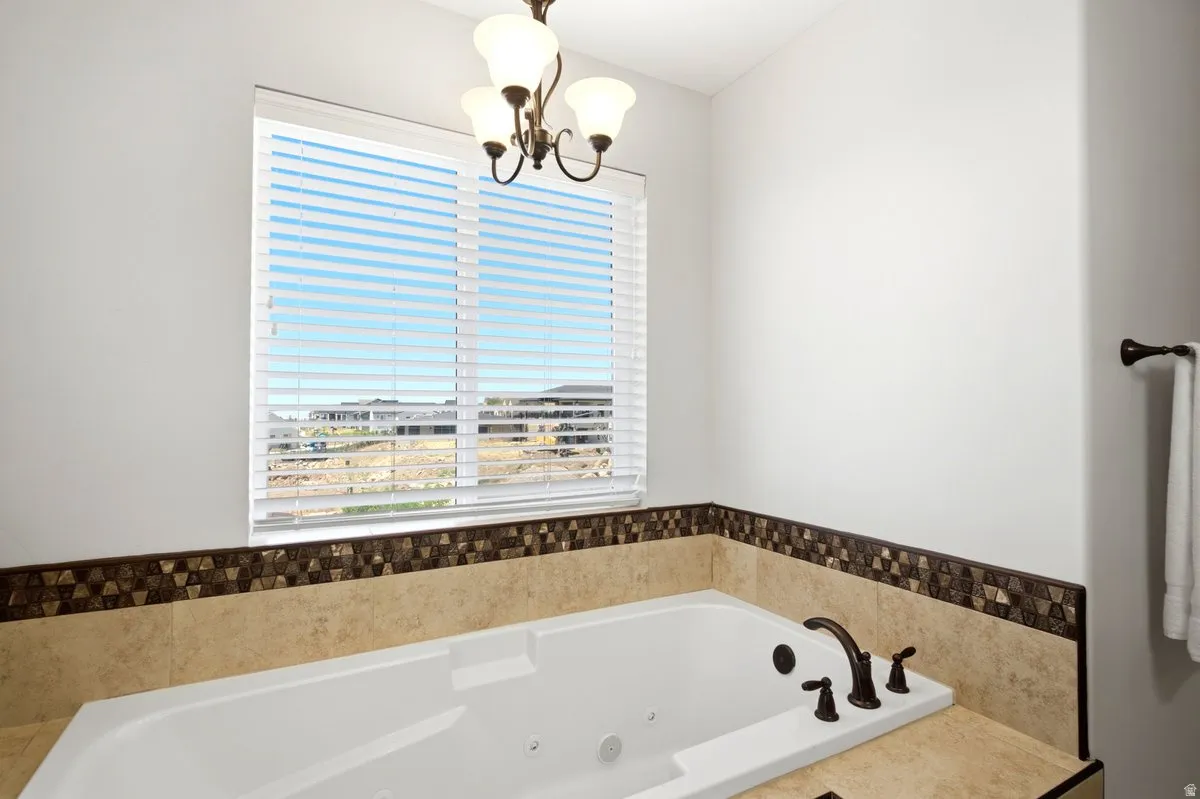 Built-in jetted tub with a bronze-finish faucet, surrounded by a tiled deck and decorative mosaic tile accent