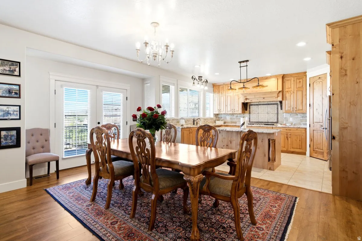 Open-concept living space featuring wood-finish flooring, a kitchen with light wood cabinetry, a central island, and a tiled backsplash