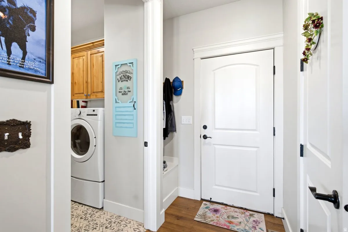 Entryway featuring a paneled door with black hardware, wood-finish flooring, and white baseboards