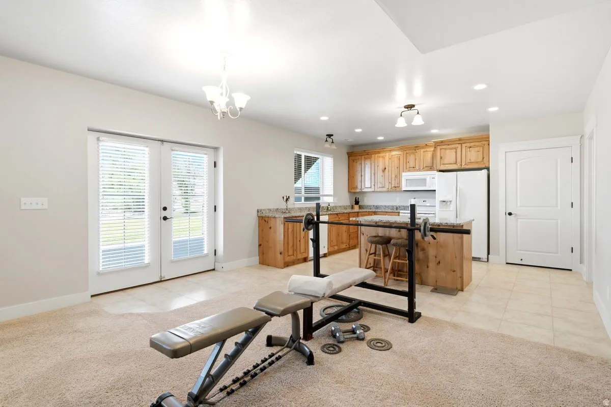 Bright interior space with French doors and a full kitchen featuring wood cabinetry, white appliances, and a kitchen island with seating