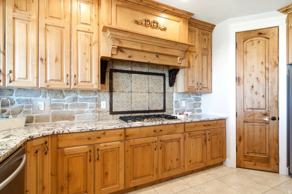 Kitchen featuring wood-finish cabinetry, granite countertops, and a stone-tile backsplash