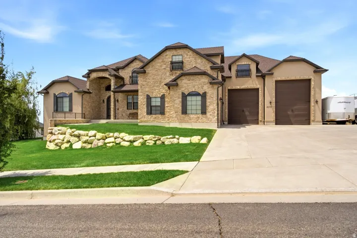 Stone and stucco exterior residence featuring a prominent arched entry, dark window shutters, and a multi-gabled roofline