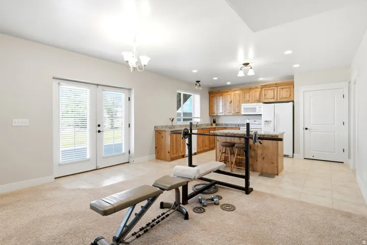 Bright interior space with French doors and a full kitchen featuring wood cabinetry, white appliances, and a kitchen island with seating