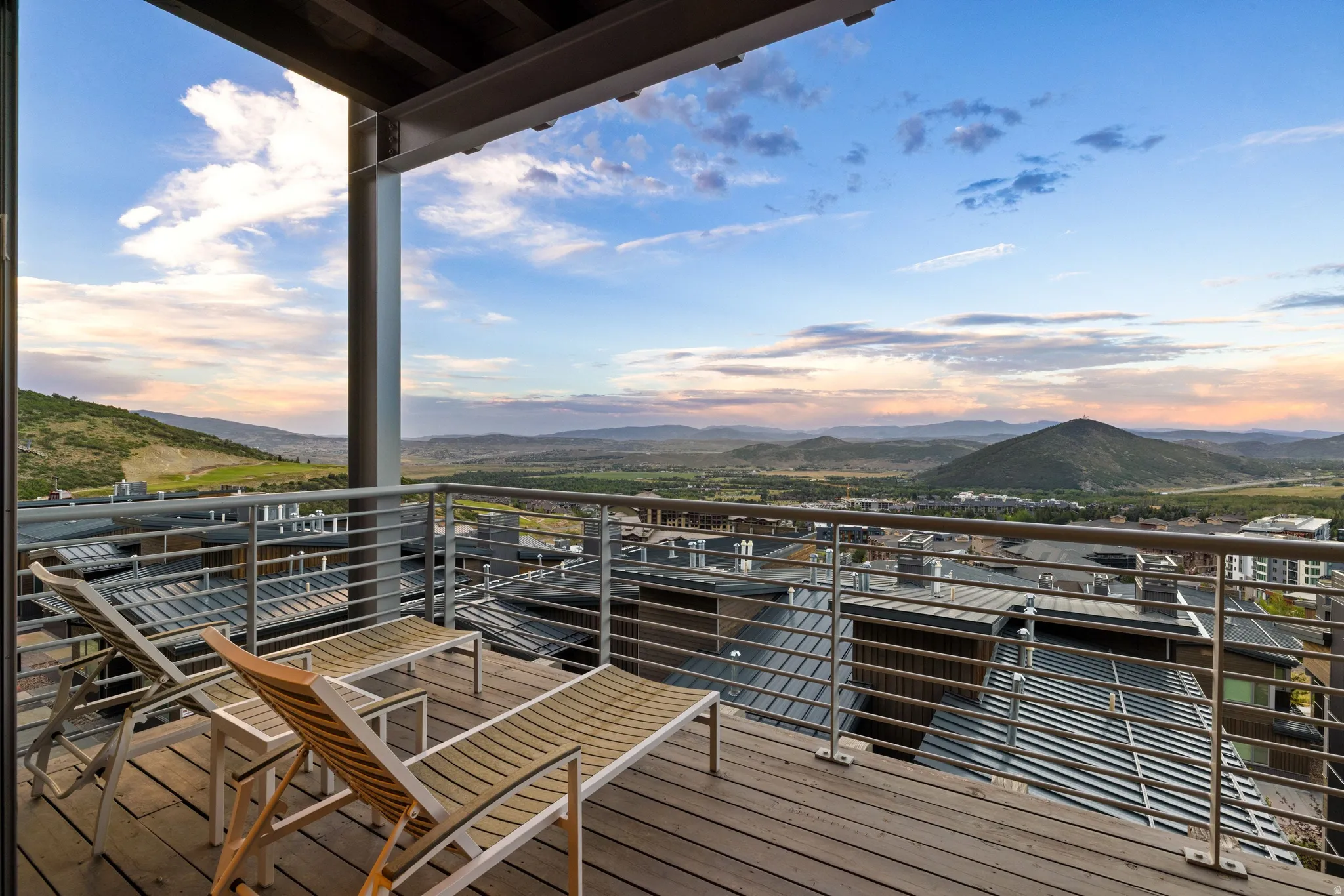Expansive outdoor deck featuring wood-finish flooring, a contemporary horizontal cable railing, and structural support beams