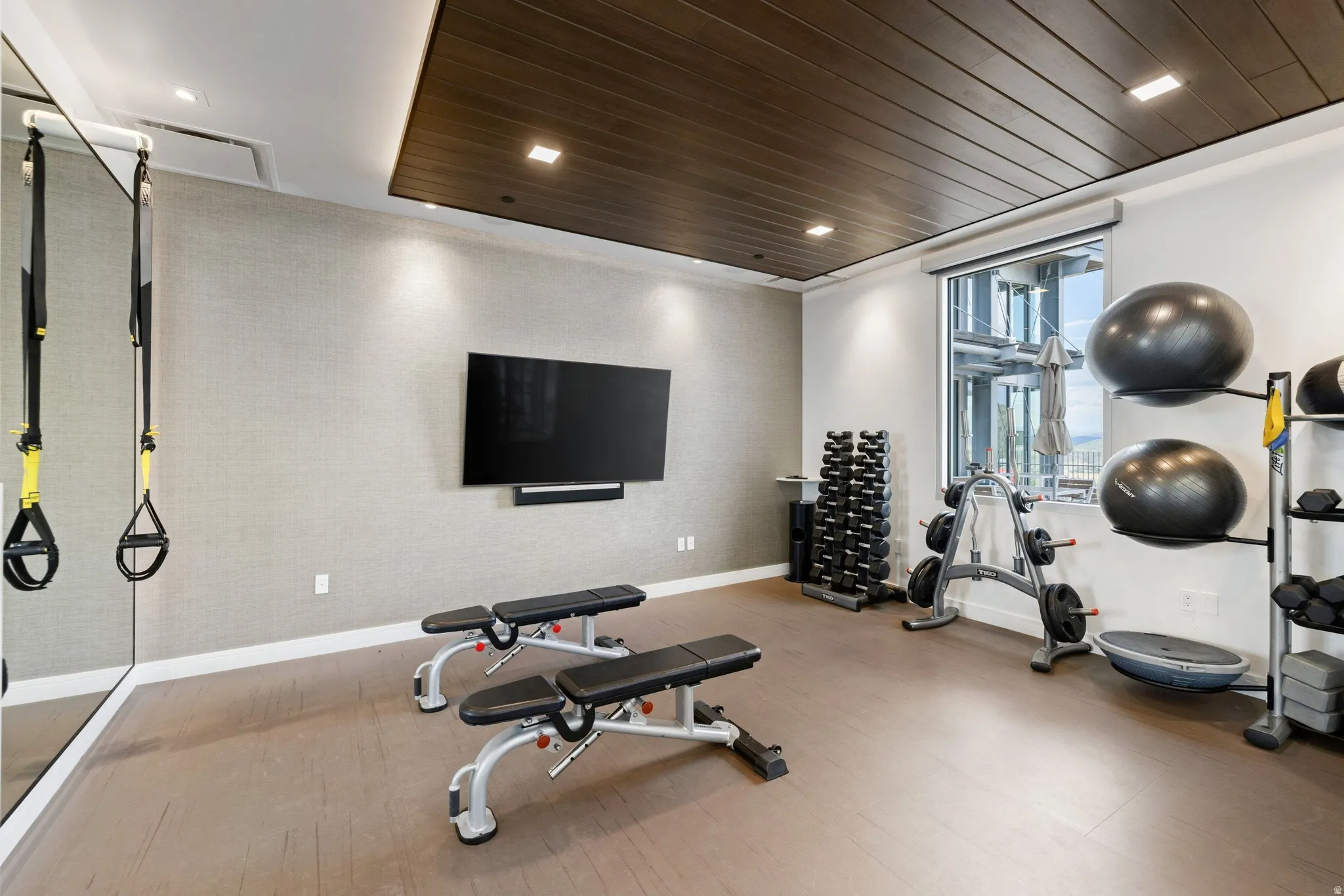 Dedicated fitness room featuring a wood-panel accent ceiling, recessed lighting, and resilient flooring
