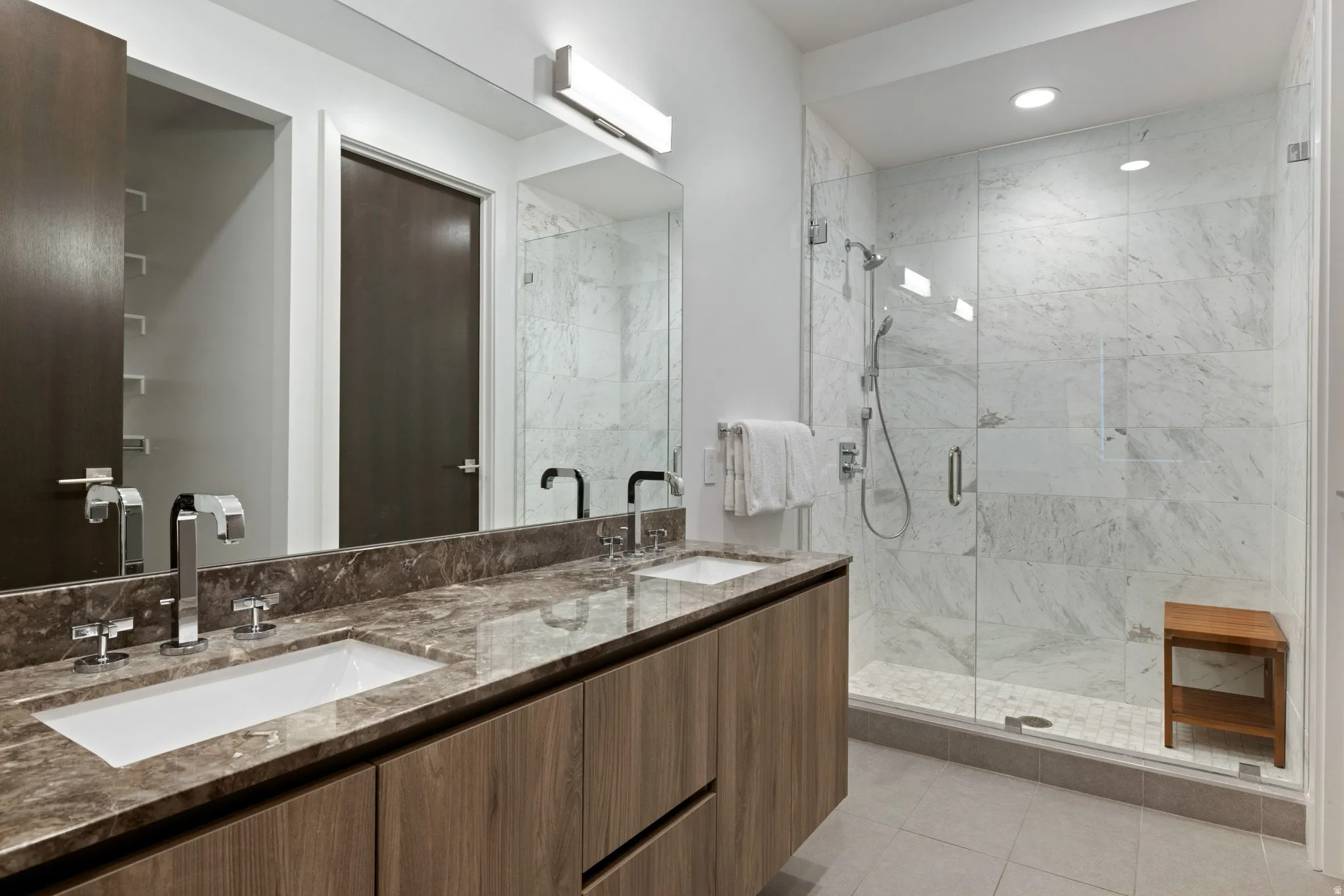 Floating wood-finish double vanity with undermount sinks and chrome fixtures
