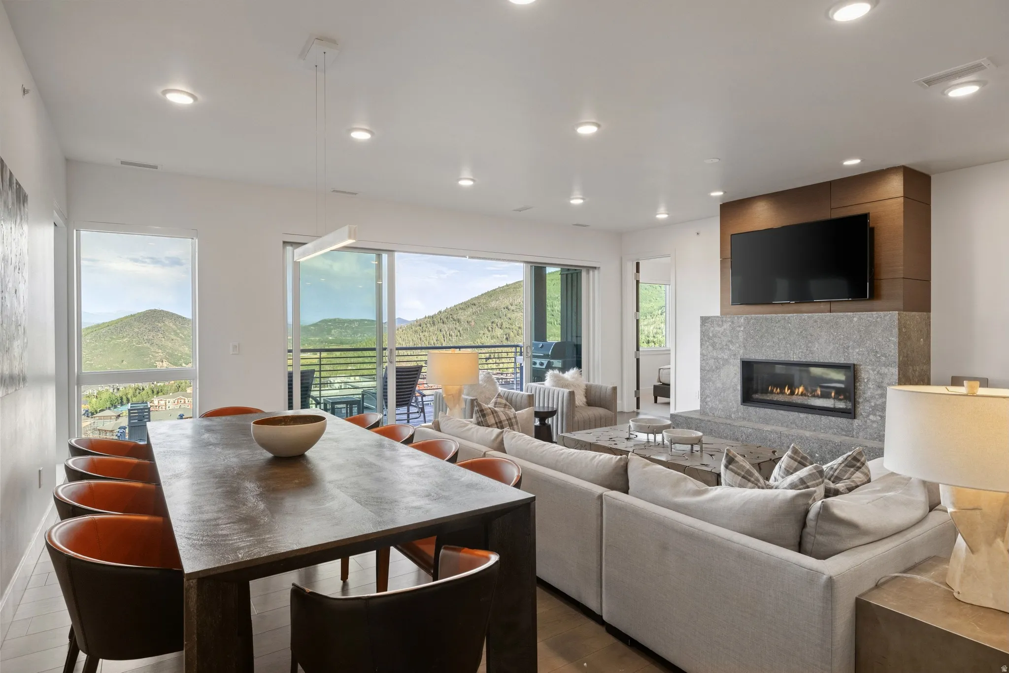 Spacious open-concept living area with a stone-clad fireplace and wood-finish accent wall