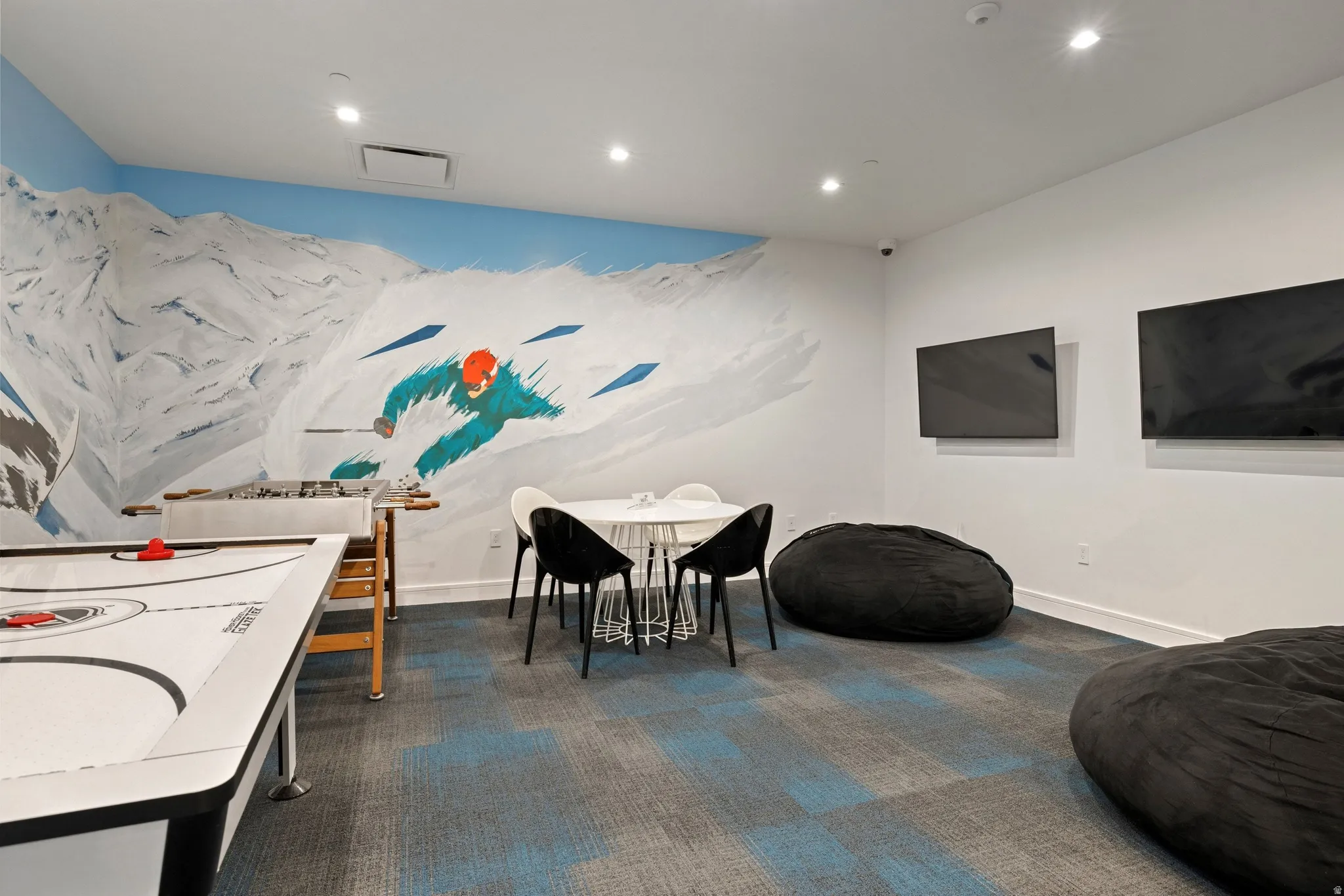Recreational space featuring a vibrant mountain mural, recessed lighting, and patterned carpet flooring