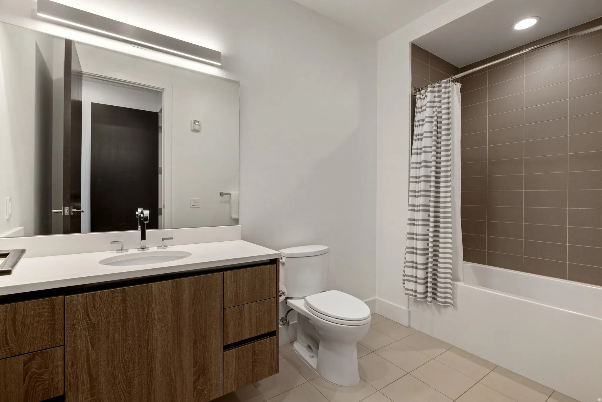 Modern bathroom featuring a wood-finish vanity with a white countertop and undermount sink