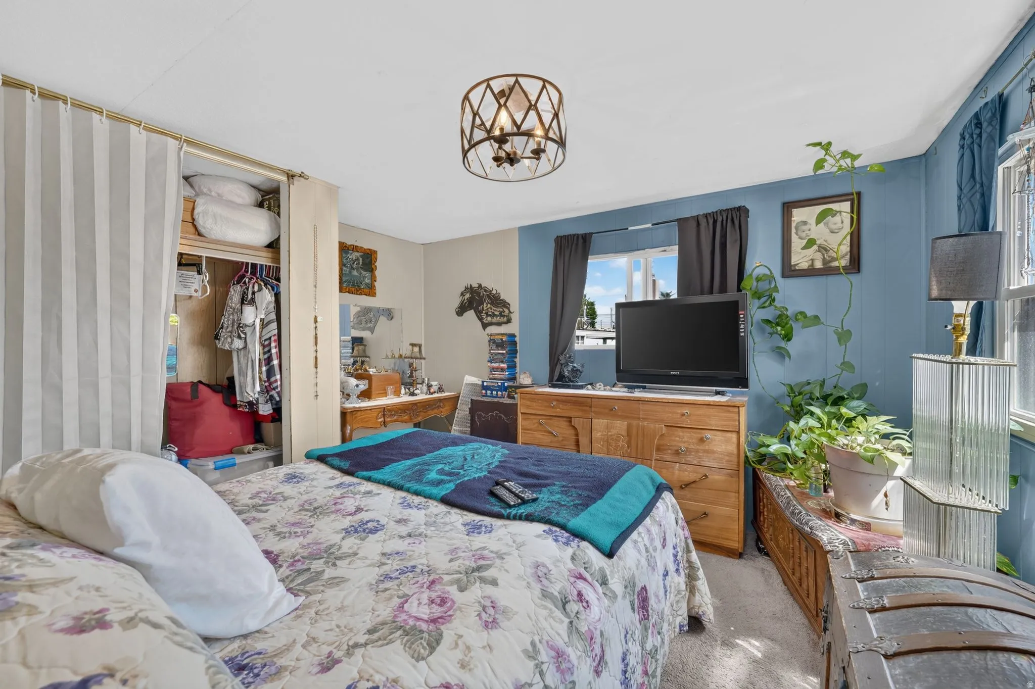 Bedroom featuring a ceiling-mounted light fixture, carpeted flooring, and a window with dark curtains
