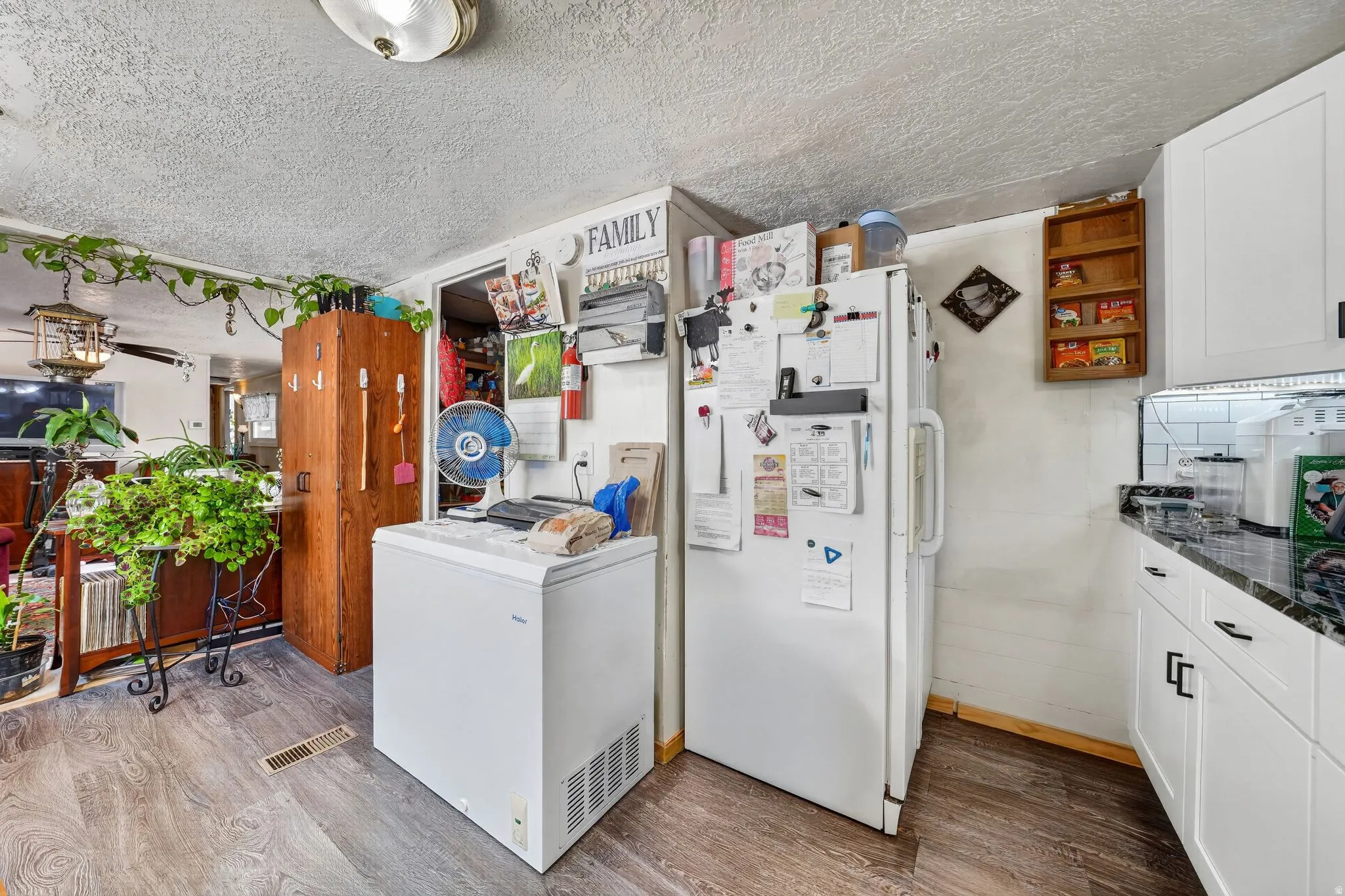 Kitchen area featuring white cabinetry with black hardware, black granite-look countertops, and white subway tile backsplash
