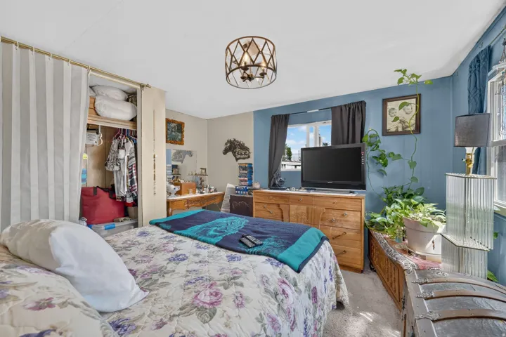 Bedroom featuring a ceiling-mounted light fixture, carpeted flooring, and a window with dark curtains