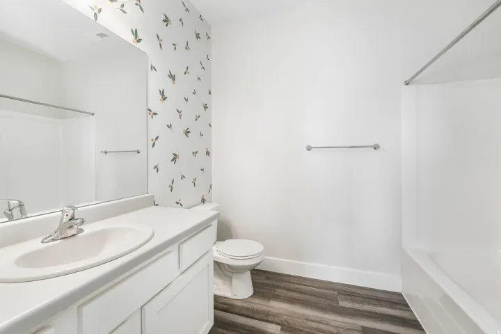 Bathroom featuring a white vanity with integrated sink, chrome faucet, and a large wall mirror