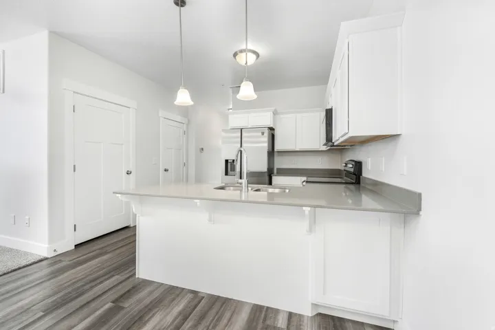 Kitchen island with integrated sink and chrome faucet, under two pendant lights