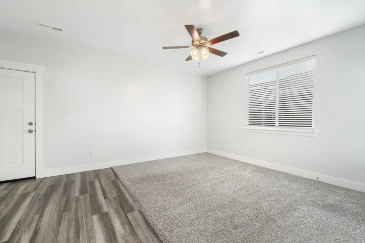 Spacious room featuring a partial wood-finish flooring entry leading to plush gray carpeting