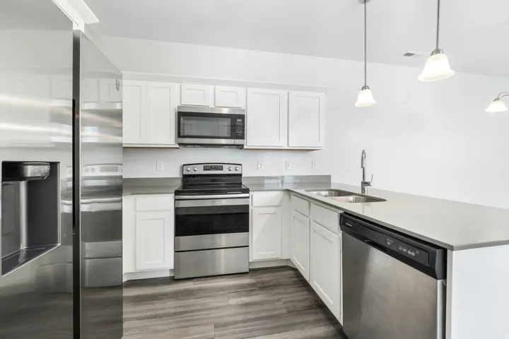 Kitchen featuring white cabinetry, wood-finish flooring, and stainless steel appliances including a refrigerator, range, microwave, and dishwasher