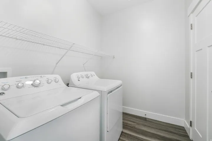 Dedicated laundry area featuring wire shelving, wood-finish flooring, white baseboards, and a white interior door