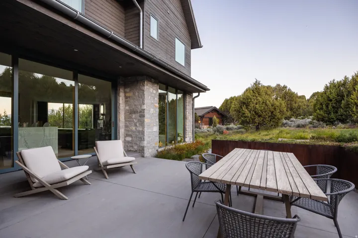 Expansive patio featuring a concrete surface, stone wall accents, and floor-to-ceiling glass doors