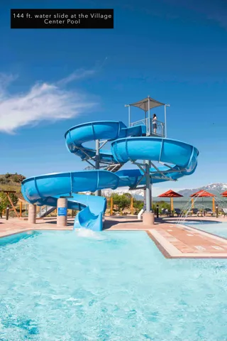 Multi-level water slide structure with a blue finish, featuring a top platform with a shaded canopy