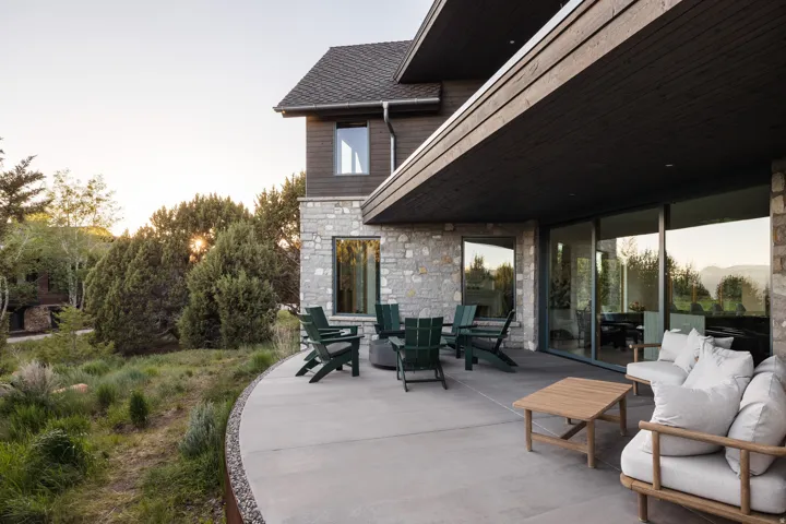 Expansive curved concrete patio featuring a stone veneer exterior and large format sliding glass doors