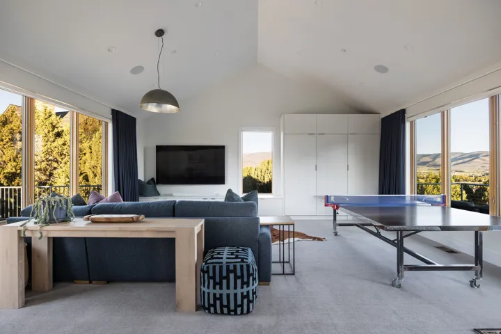 Spacious room featuring vaulted ceilings, large windows with natural scenery, recessed lighting, and built-in storage cabinetry