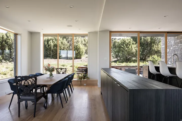 Open-concept dining and kitchen space featuring wood-finish flooring, recessed lighting, and expansive windows