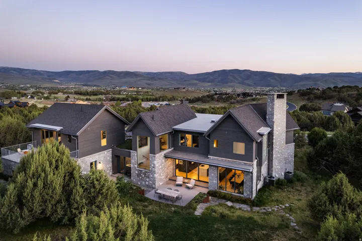Modern residence featuring a dark gray exterior with stone accents and multiple large windows