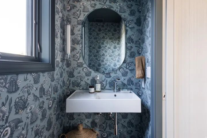 Powder room with a floating vanity, single basin sink, and wall-mounted faucet