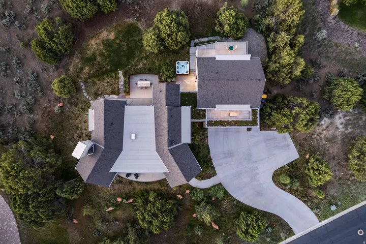 Modern residence featuring multiple rooflines, a curved driveway, and a private patio with a built-in spa