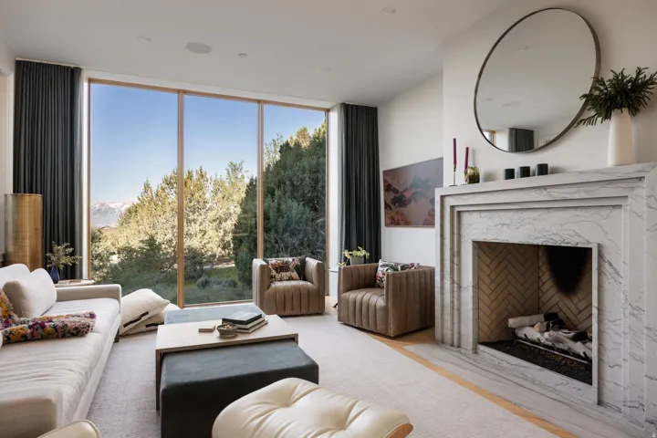 Spacious living area featuring floor-to-ceiling windows, a contemporary marble-clad fireplace, and recessed lighting