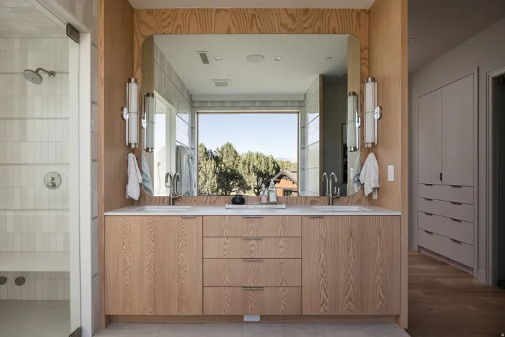 Double vanity featuring light wood cabinetry, white countertops, and dual undermount sinks