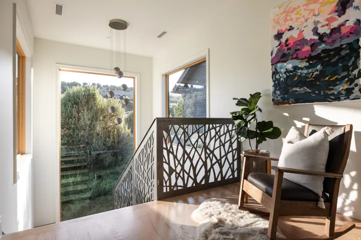 Open-concept upper landing featuring wood-finish flooring, a contemporary chandelier, and large picture windows