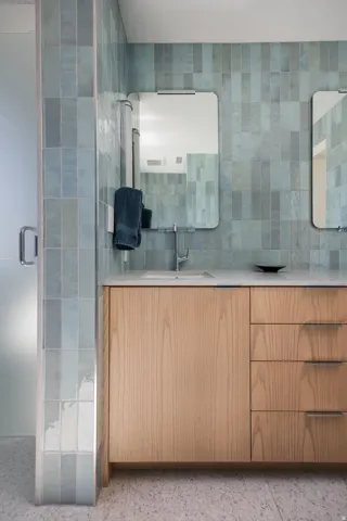 Bathroom vanity featuring light wood-finish cabinetry, integrated sink, and stone countertop