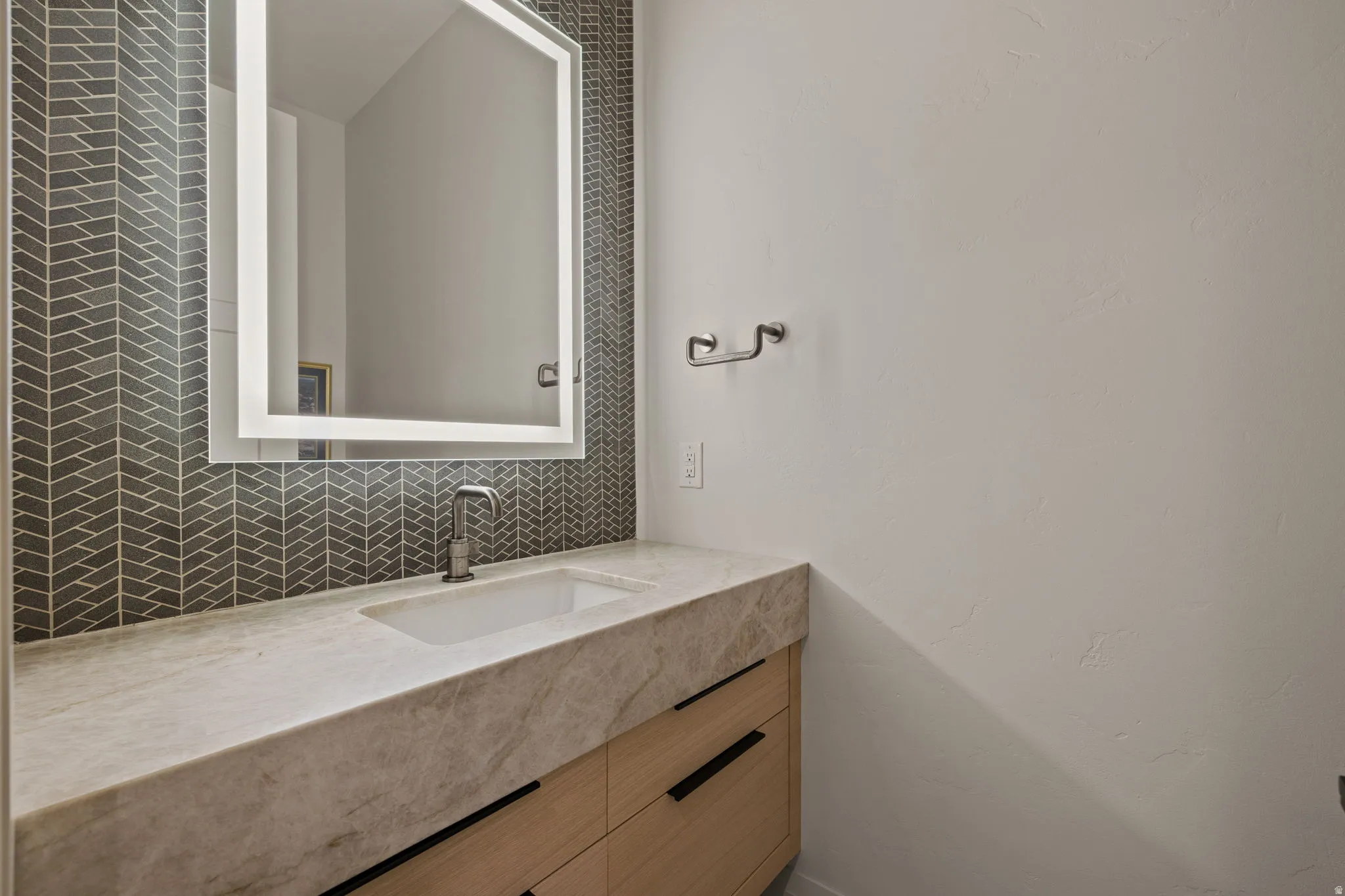 Bathroom vanity with an integrated rectangular sink, light-toned stone countertop, and wood-finish cabinetry