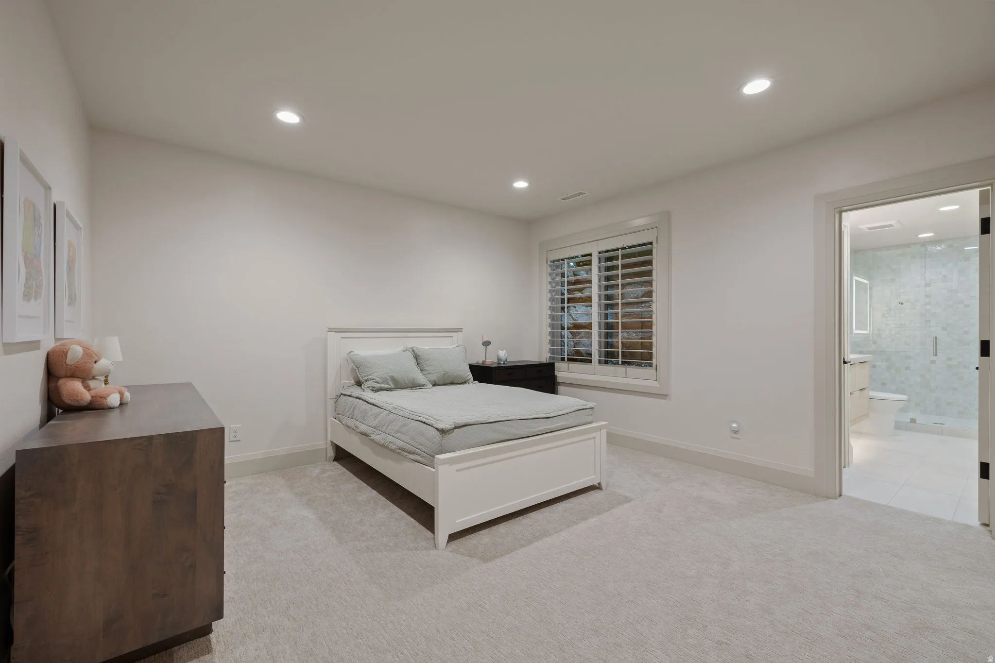 Carpeted room with recessed lighting and a window featuring white plantation shutters