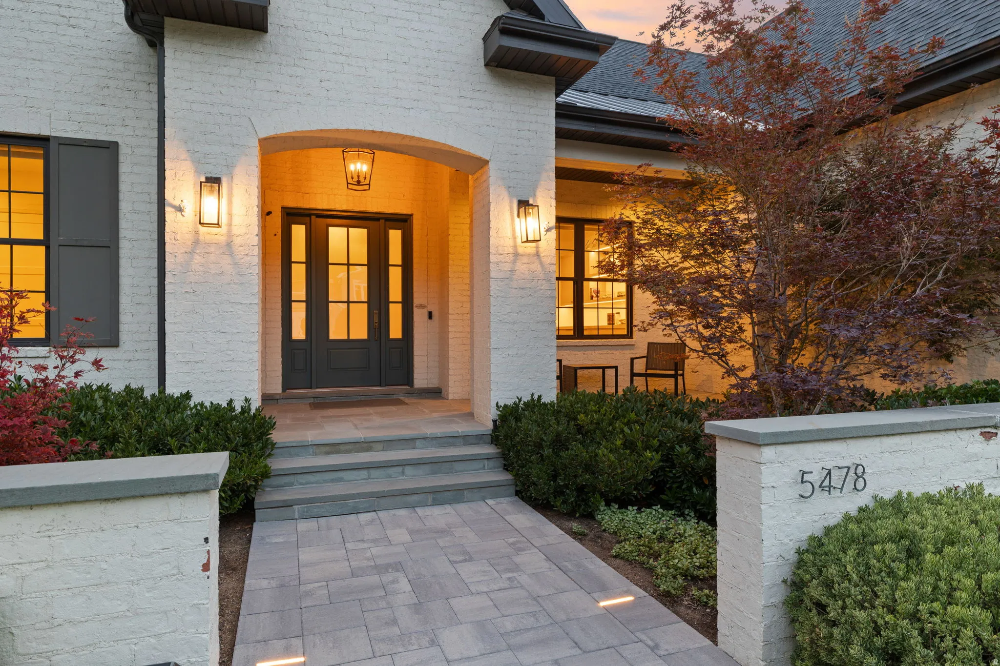 Front exterior featuring a painted brick facade, arched entryway, and dark-framed double doors with transom windows