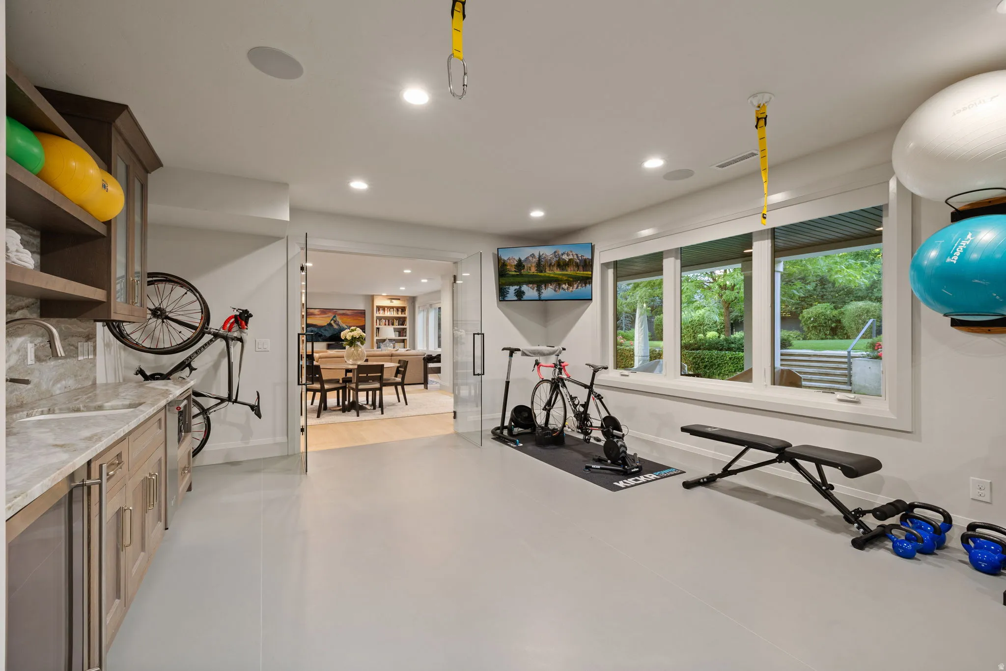 Versatile recreation room featuring light-toned flooring, recessed lighting, and a wall of windows
