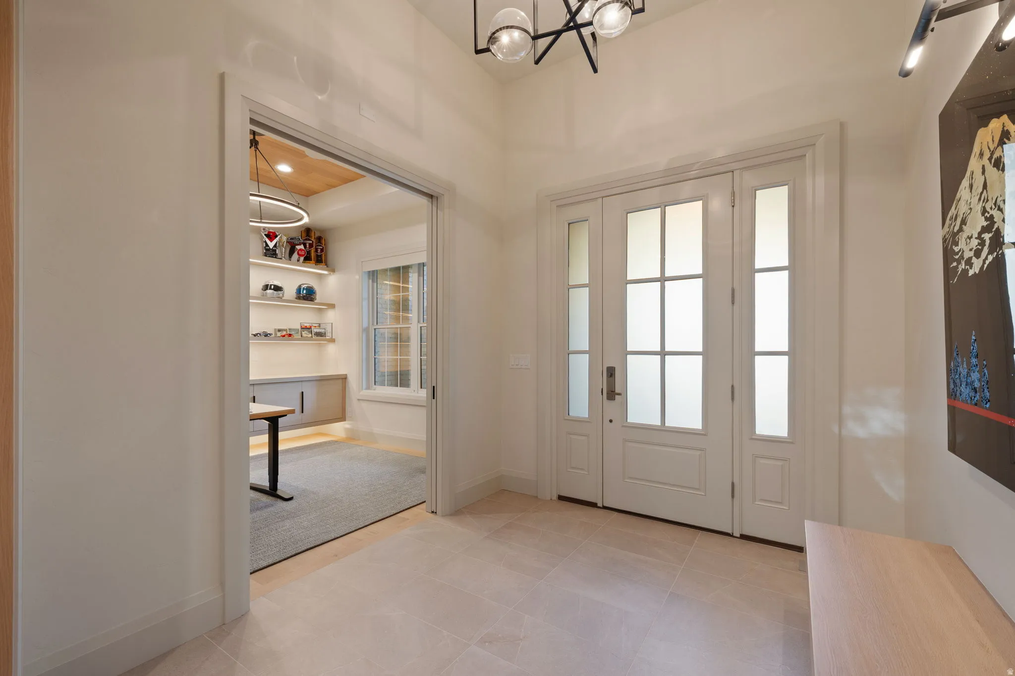 Entry foyer featuring light-toned tile flooring and a central door with two frosted glass sidelights