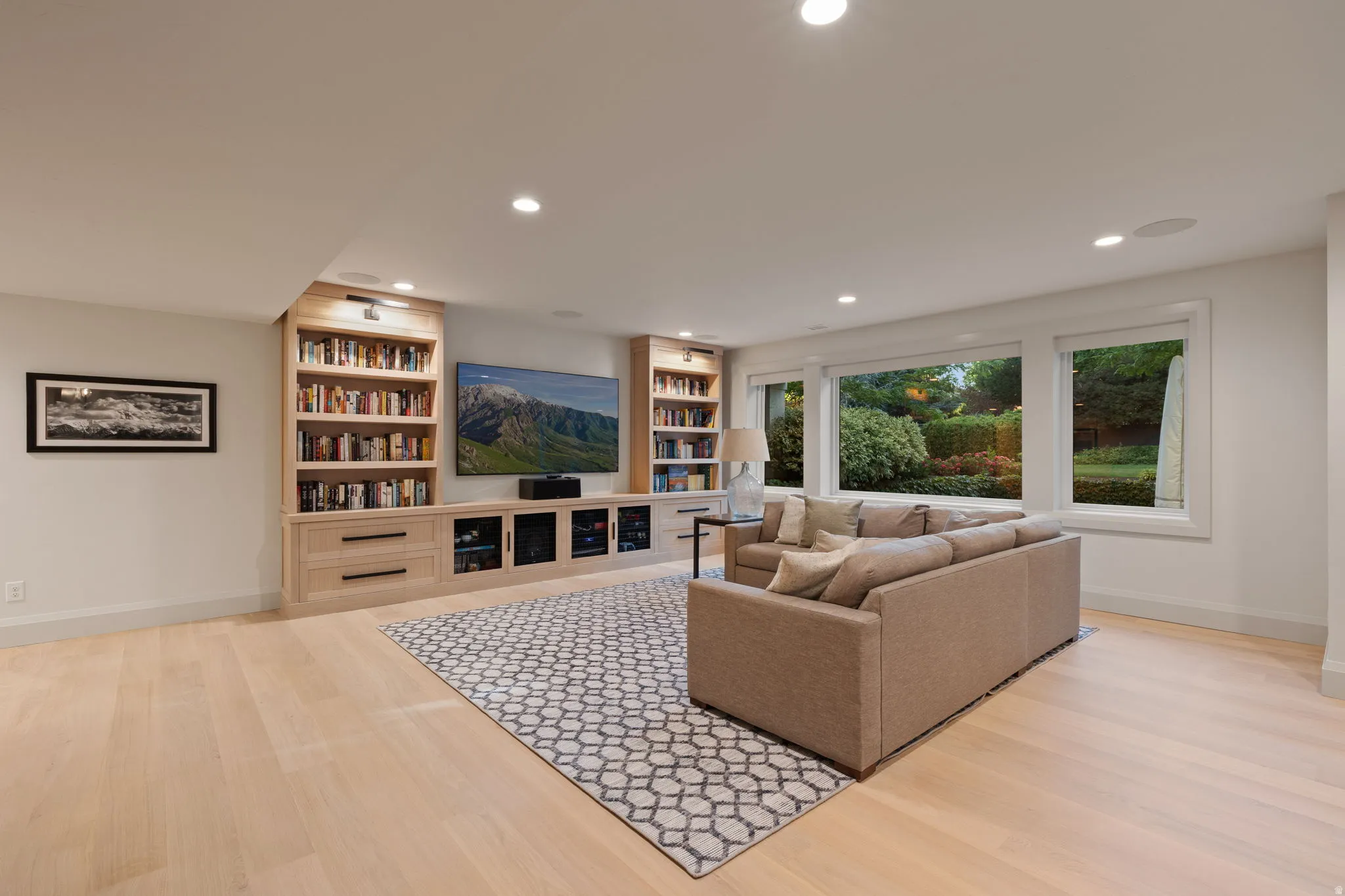 Living area featuring extensive built-in cabinetry, an entertainment center with display shelving, recessed lighting, and light wood-finish flooring