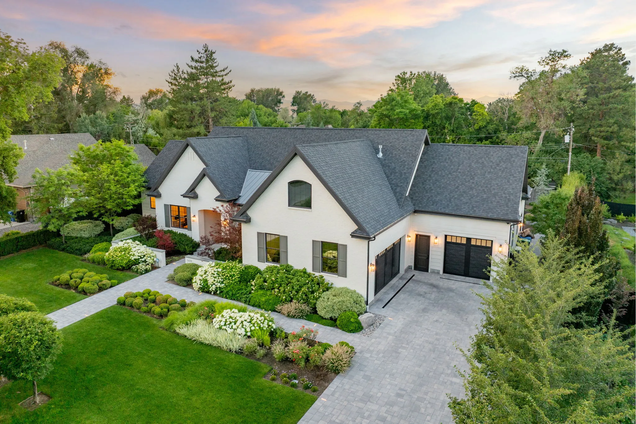 Stately white residence featuring a multi-gabled roofline and an attached three-car garage with black doors