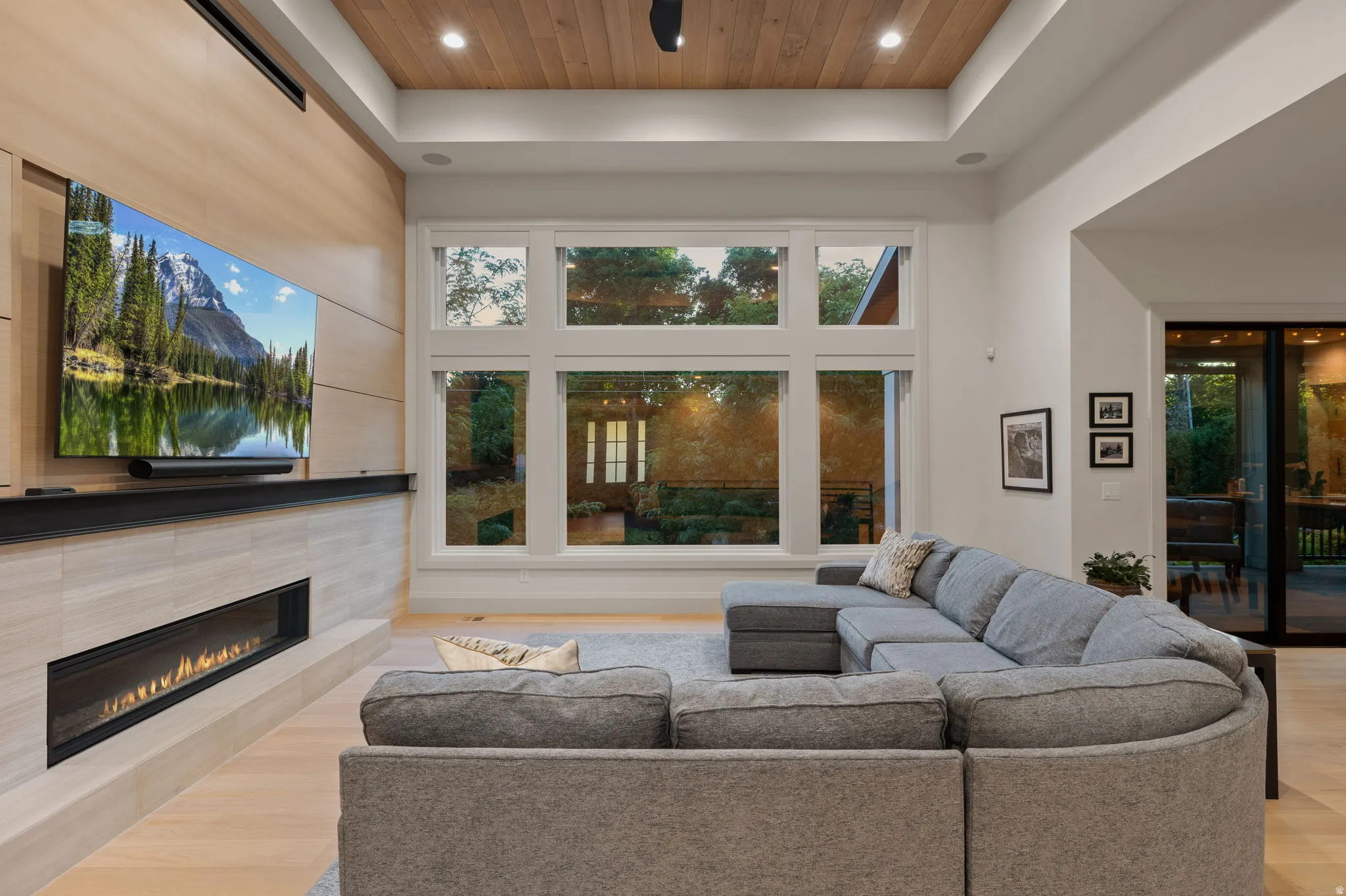 Living area featuring large multi-pane windows, a recessed ceiling with wood-finish paneling, and light wood-finish flooring